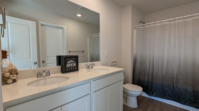 full bath featuring double vanity, toilet, wood finished floors, and a sink