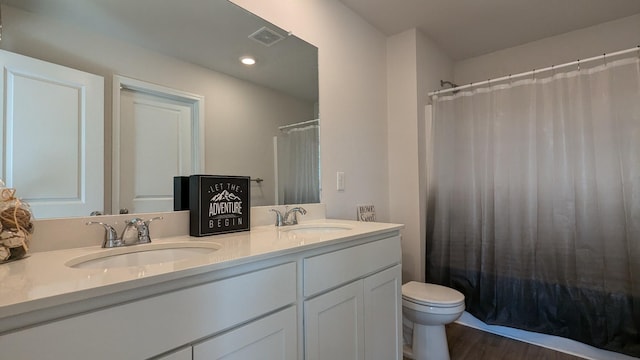 full bath featuring a sink, visible vents, toilet, and double vanity