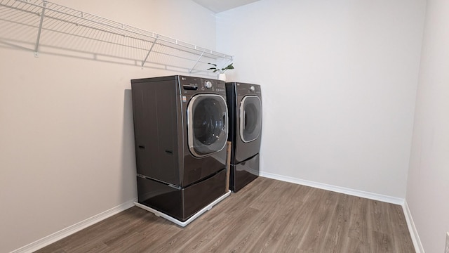 laundry area with washer and dryer, laundry area, wood finished floors, and baseboards