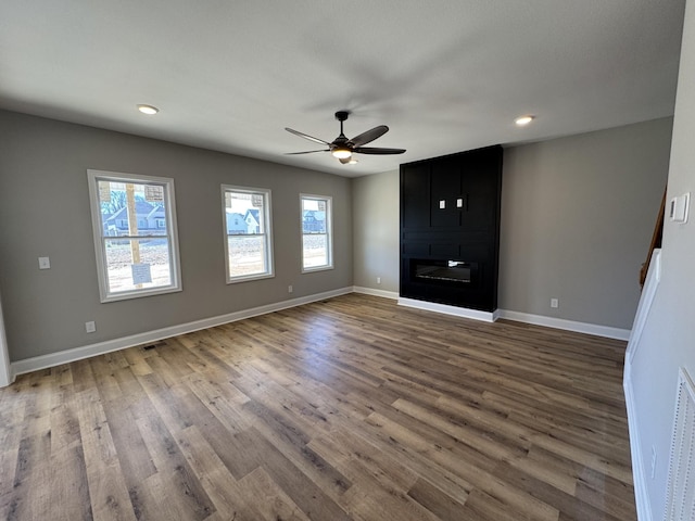 unfurnished living room with plenty of natural light, a fireplace, baseboards, and wood finished floors