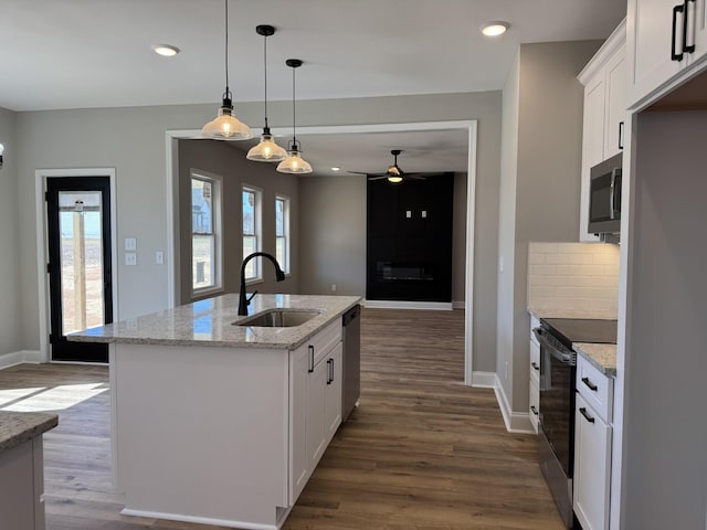 kitchen with decorative backsplash, stainless steel appliances, dark wood-style floors, white cabinetry, and a sink