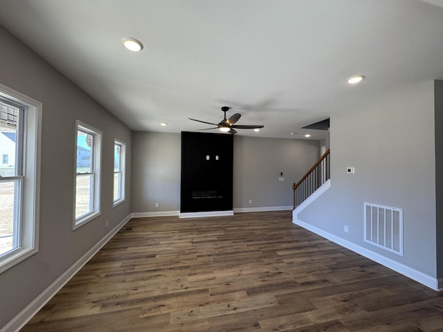 unfurnished living room featuring baseboards, visible vents, dark wood finished floors, recessed lighting, and stairs