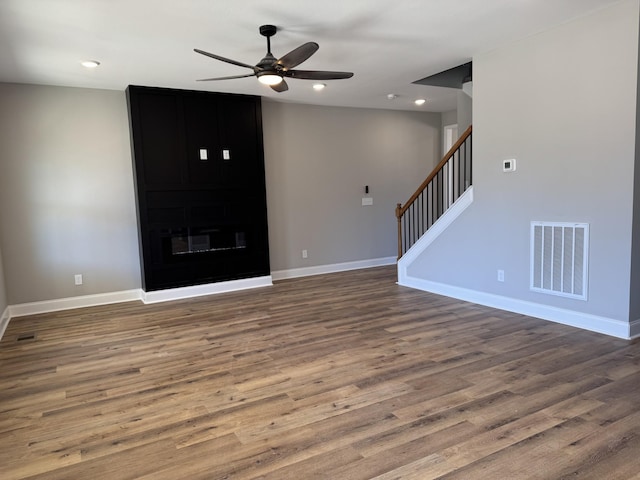 unfurnished living room with stairway, wood finished floors, visible vents, baseboards, and recessed lighting