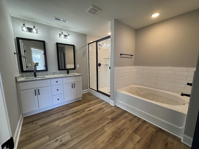 full bathroom with visible vents, a stall shower, a sink, wood finished floors, and a bath