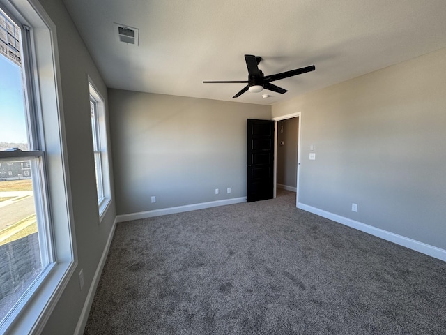 carpeted spare room featuring visible vents, a ceiling fan, and baseboards