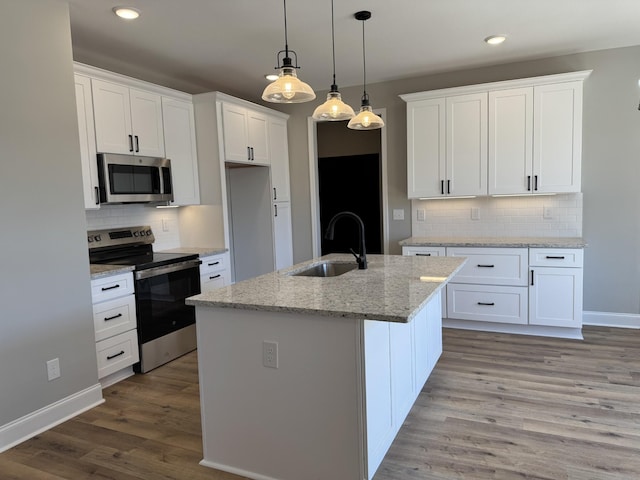 kitchen featuring a sink, appliances with stainless steel finishes, wood finished floors, white cabinets, and a kitchen island with sink