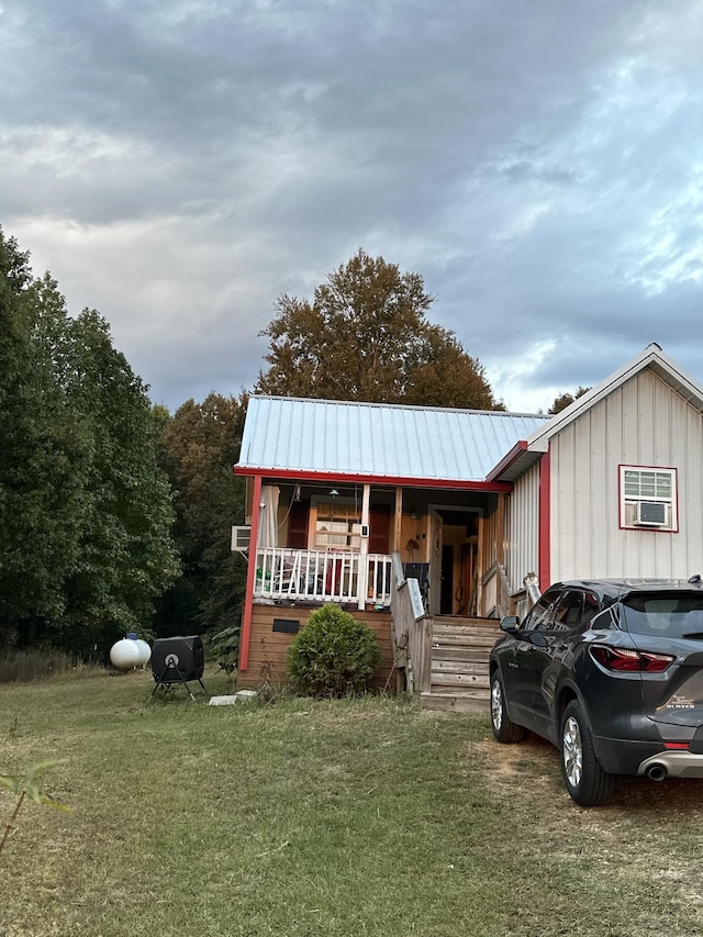 view of front of home featuring board and batten siding, a porch, a front yard, and metal roof