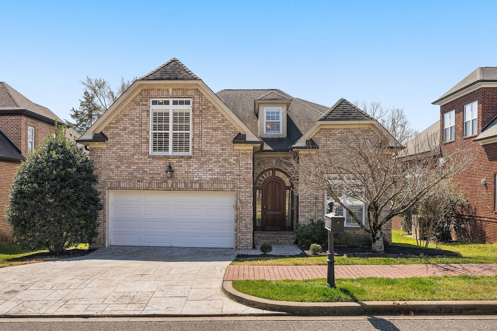 view of front facade with brick siding, concrete driveway, and a front yard