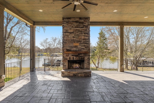 view of patio with an outdoor stone fireplace and a ceiling fan