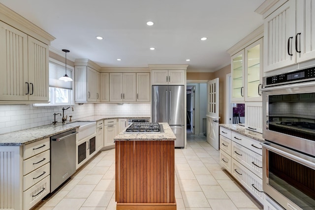 kitchen with a sink, stainless steel appliances, a kitchen island, and backsplash