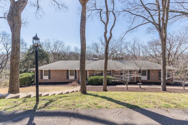 ranch-style home featuring brick siding and a front lawn