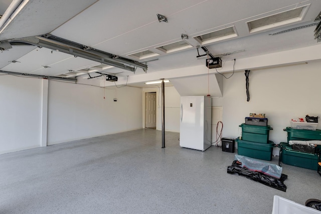 garage featuring a garage door opener and freestanding refrigerator