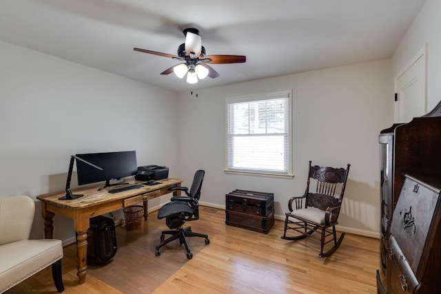 office space with light wood-style flooring, a ceiling fan, and baseboards