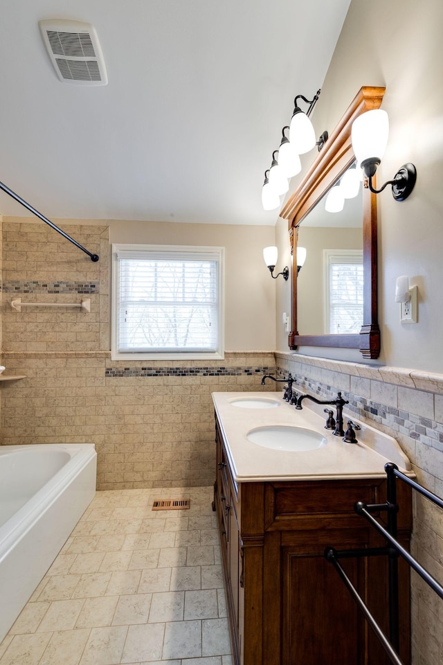 bathroom featuring visible vents, tile walls, and a healthy amount of sunlight