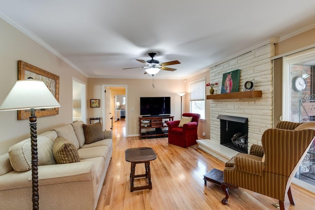 living room with a stone fireplace, ceiling fan, light wood-style floors, and ornamental molding