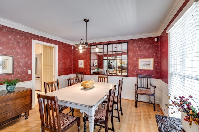 dining room featuring a wainscoted wall, light wood-style floors, a chandelier, and wallpapered walls