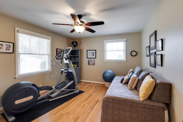 workout room featuring baseboards, light wood-style floors, and ceiling fan