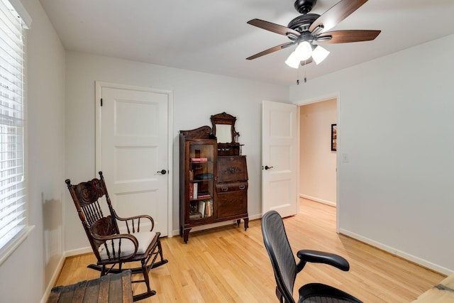 office space with baseboards, light wood-type flooring, and ceiling fan