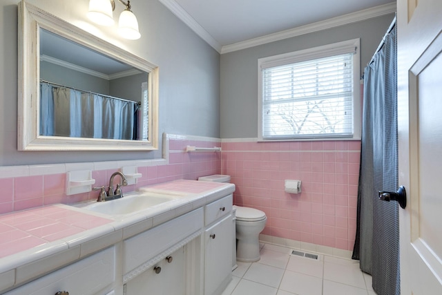 bathroom featuring tile patterned flooring, visible vents, vanity, ornamental molding, and tile walls