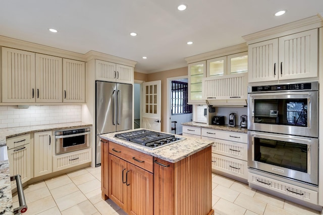 kitchen with backsplash, light stone countertops, light tile patterned floors, cream cabinets, and stainless steel appliances