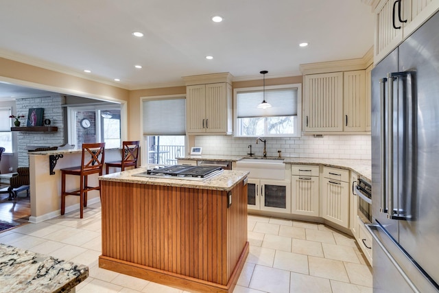 kitchen featuring cream cabinetry, ornamental molding, tasteful backsplash, a kitchen island, and stainless steel appliances