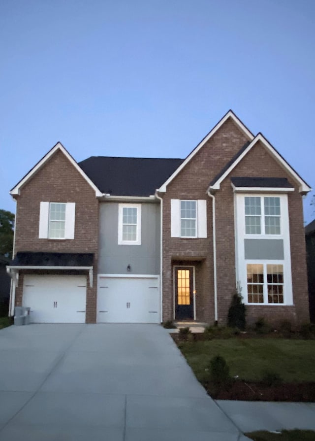 view of front of property with brick siding, an attached garage, concrete driveway, and a front lawn