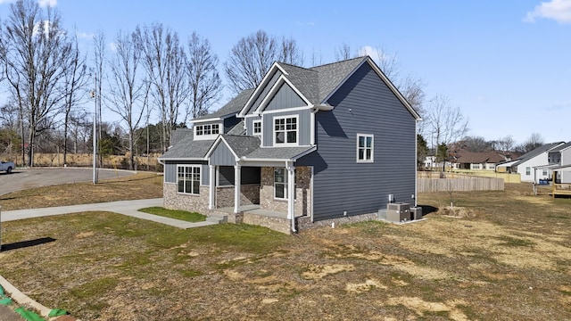 view of front of property with stone siding, board and batten siding, central AC, and roof with shingles