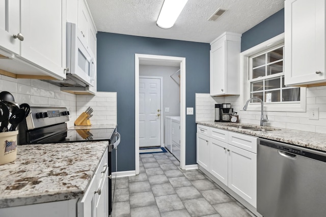 kitchen with visible vents, a sink, white cabinetry, separate washer and dryer, and appliances with stainless steel finishes