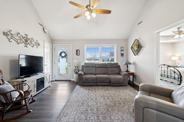 living room featuring dark wood finished floors, visible vents, ceiling fan, and vaulted ceiling