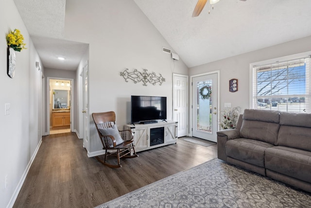 living area featuring visible vents, high vaulted ceiling, dark wood-type flooring, a ceiling fan, and baseboards