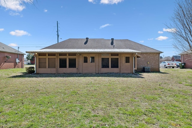 rear view of house with a yard, brick siding, and central AC