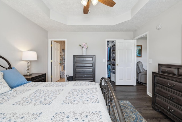 bedroom with dark wood-type flooring, a spacious closet, a closet, a textured ceiling, and a raised ceiling