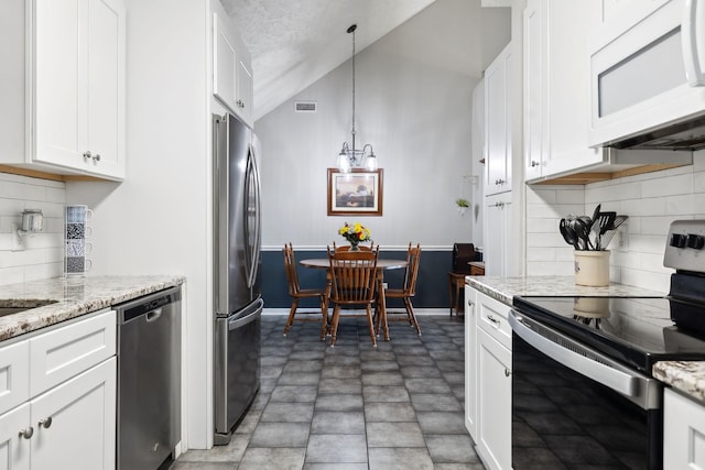 kitchen featuring light stone counters, visible vents, lofted ceiling, white cabinets, and appliances with stainless steel finishes