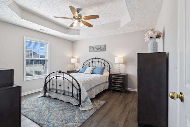 bedroom with a raised ceiling, baseboards, dark wood-style flooring, and a textured ceiling