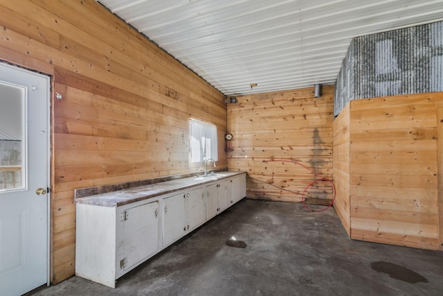 interior space featuring wooden walls, concrete floors, and a sink