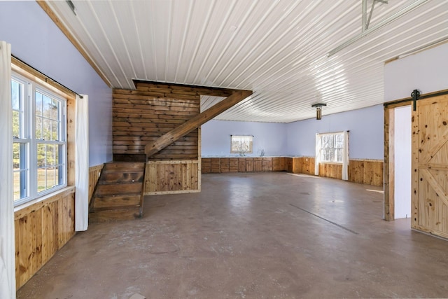 below grade area featuring wooden walls, a barn door, and a wainscoted wall