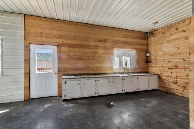 interior space with white cabinetry, concrete flooring, and a sink