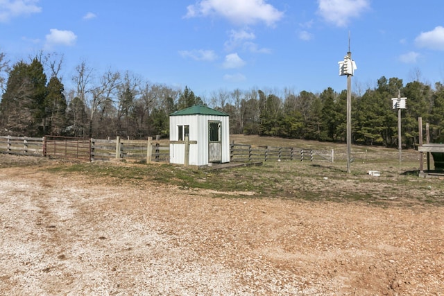 view of outdoor structure featuring an outbuilding, a rural view, and fence