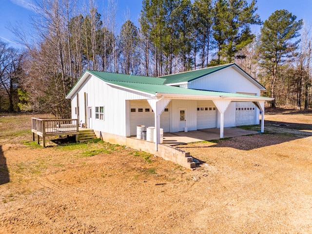 view of property exterior with a deck, driveway, and metal roof