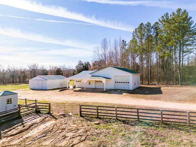 exterior space featuring fence, a pole building, an outdoor structure, a rural view, and a garage