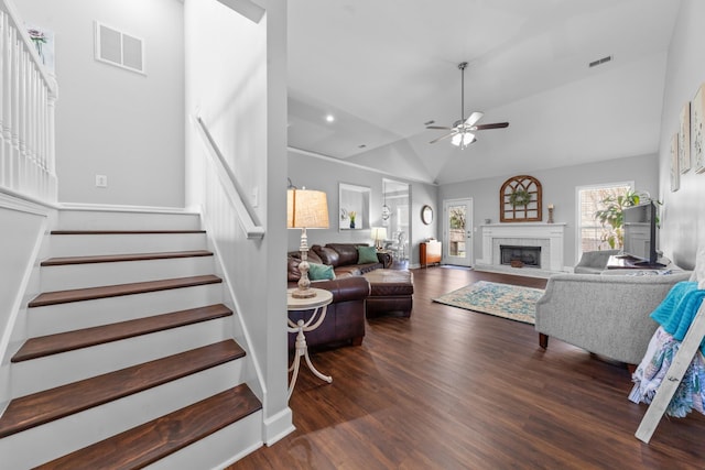 living room featuring visible vents, a fireplace with raised hearth, ceiling fan, stairs, and wood finished floors