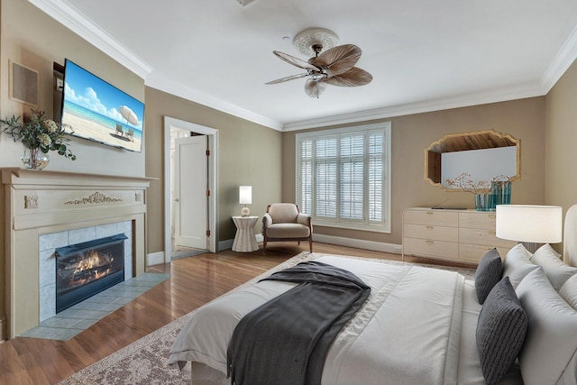 bedroom featuring a fireplace, wood finished floors, ceiling fan, and ornamental molding