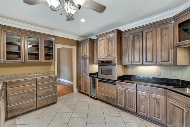 kitchen featuring stainless steel oven, glass insert cabinets, ceiling fan, and light tile patterned floors