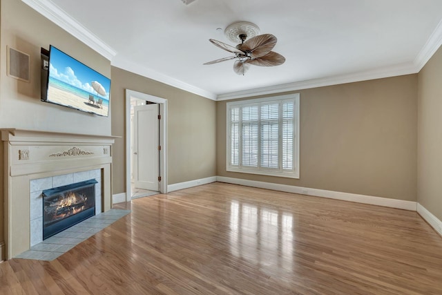 unfurnished living room featuring a fireplace, crown molding, baseboards, and wood finished floors