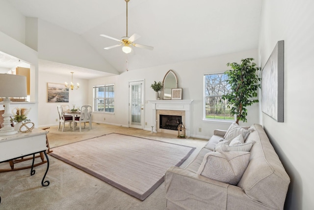 carpeted living room with baseboards, high vaulted ceiling, a fireplace, and ceiling fan with notable chandelier