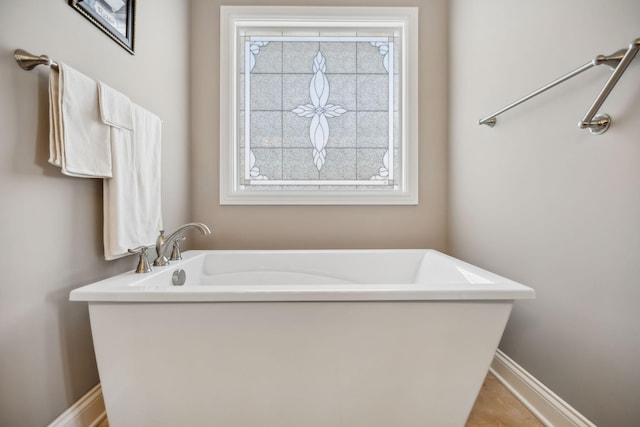 full bath featuring baseboards, plenty of natural light, and a freestanding bath