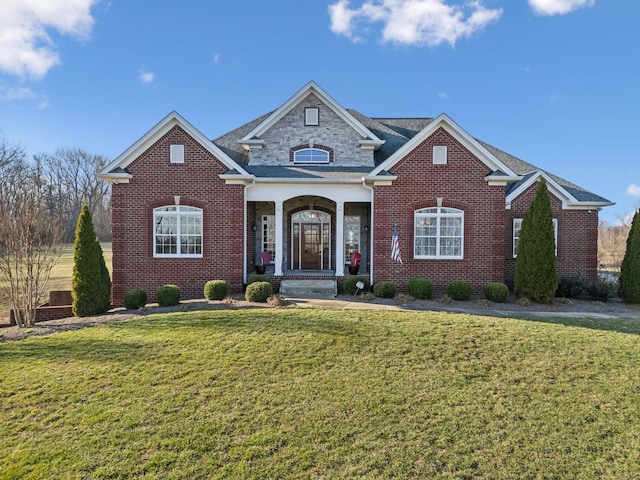 view of front of property featuring brick siding, covered porch, and a front yard