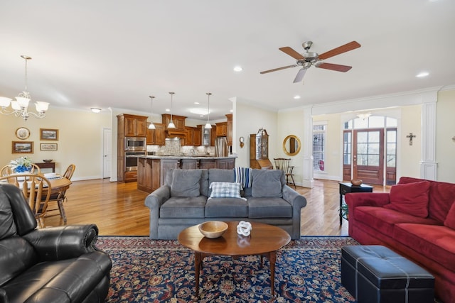 living area featuring ceiling fan with notable chandelier, recessed lighting, crown molding, light wood finished floors, and baseboards