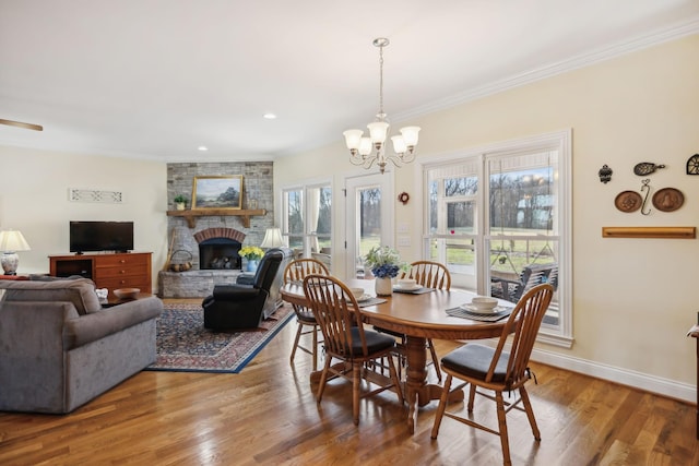 dining room with ornamental molding, a fireplace, baseboards, and wood finished floors