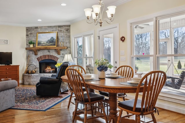 dining area with plenty of natural light, a fireplace, wood finished floors, and ornamental molding